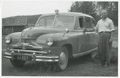 SKS:n auto ja vahtimestari Reino Rautavaara vuonna 1954. Standard Vanguard -merkkinen äänitysauto oli hankittu Oy Karl Fazer Ab:n lahjoittamilla varoilla. Kuva: 1954 (SKS, kirjallisuusarkisto).